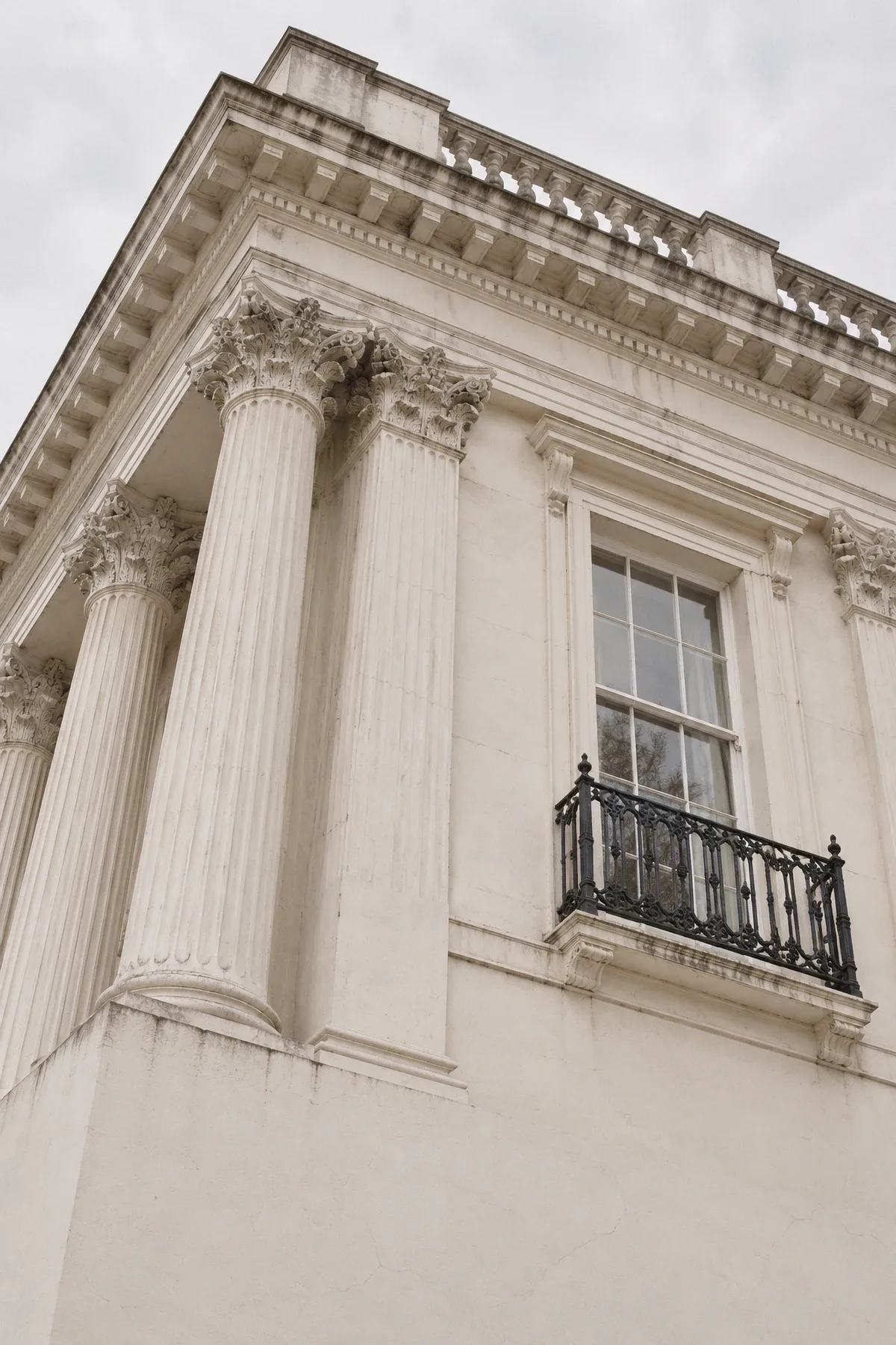 Looking up at the white stucco columns and cornice of a Regency terrace in London.